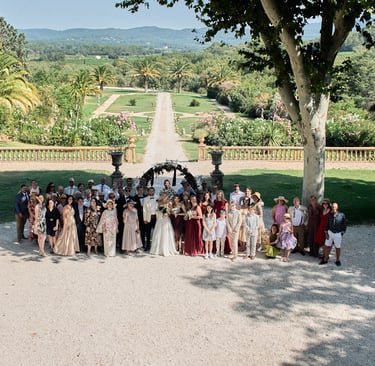 Group photo of wedding guests in the garden of a French château during an American wedding