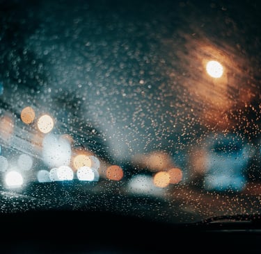 Road and City Lights blurred through a rainy windshield Photo by Ugur Tandogan (Pexels.com)