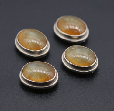 A sleek black velvet display showcasing a pair of custom gold earrings shaped like tiny orreries.