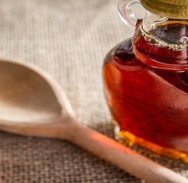 Maple syrup in a glass bottle and a wooden spatula