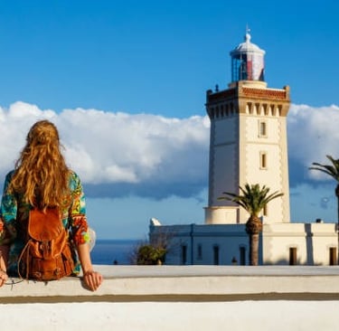 morocco tangier a woman sitting on a ledge looking at a lighthouse
