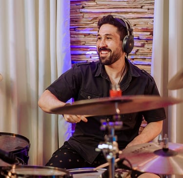 Drummer Lucas Dias playing the drums while wearing headphones.