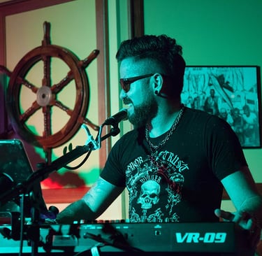 Singer Leo Couto playing a Roland keyboard, looking to the side, wearing sunglasses.