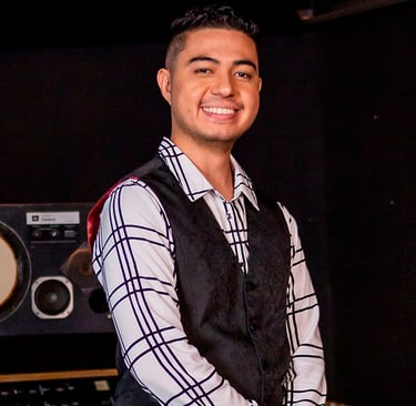 Bassist Ian Yoshio smiling, wearing a white shirt with black stripes and a black vest.