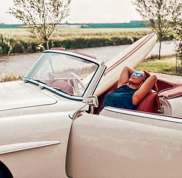 Woman relaxing in a classic convertible with a handmade balsa surfboard