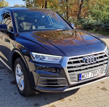 a black audi is parked on a brick road