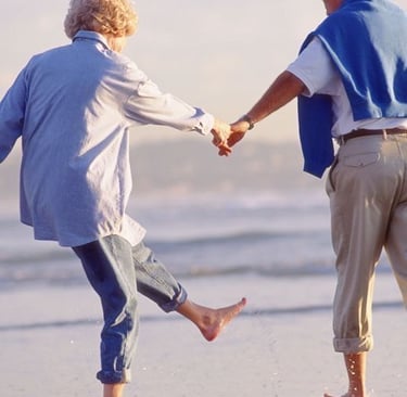 um homem e uma mulher de mãos dadas e caminhando na praia