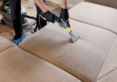 Agent de nettoyage en train de nettoyer un canapé