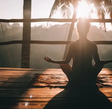 Seduta in silenzio, la ragazza è avvolta dalla luce dorata dell’alba. La sua schiena è eretta, le ma