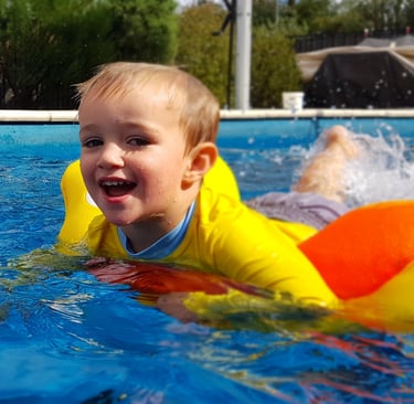 a young child on a yellow inflatable in a pool