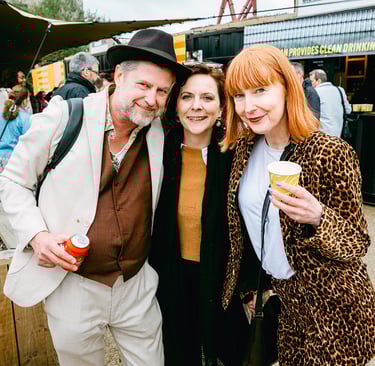 Three people smile at the camera. They are at a work conference at Riverside Park London