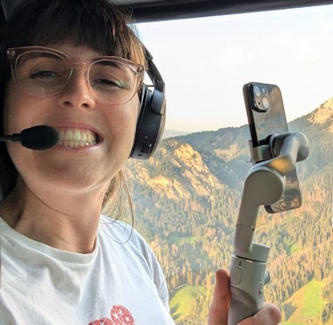 Laura sits in a helicopter over the Italian Dolomites with a gimble taking social media videos