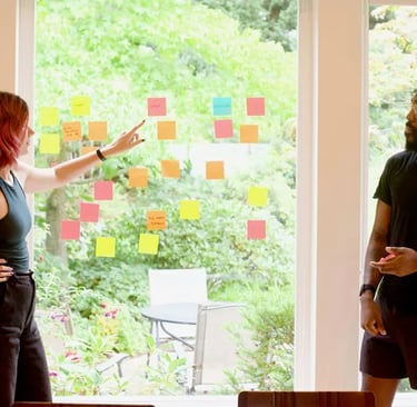 deux personnes réflechissent à leur team building à Montpellier en mettant des post-it à la fenêtre