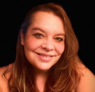 A smiling middle-aged woman with long brown hair against a dark background.