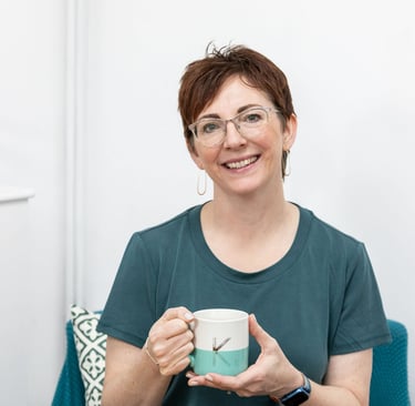 Kelly smiling holding a mug and wearing a green t shirt. 