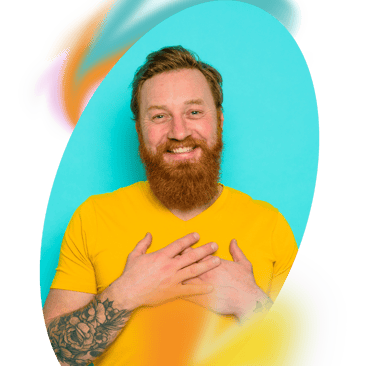a white man with a beard holding his hands to his heart and smiling