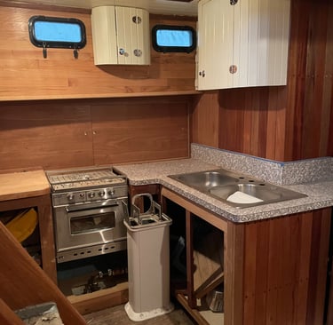 a kitchen with a sink and a gimbled stove, wood walls and sliding cabinet door