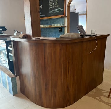 a bar counter with a wooden bar stool and a chalkboard