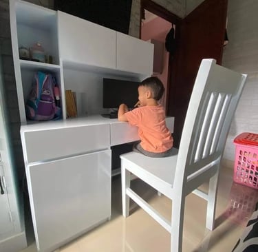 a young child sitting at a white desk made by DharmaJaya furniture Bali desk with a computer