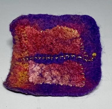 small hand felted brooch in reds and purple