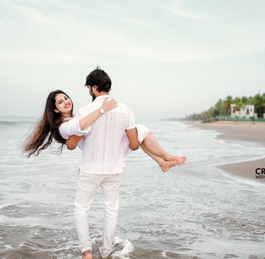 Save the date photograph groom walking on the beach lifting the bride in hand with white costumes