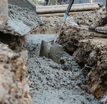 Construction worker pouring concrete for a foundation. Custom Concrete Texas: Building strong founda