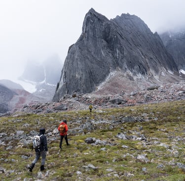 Climbers approach granite spires rising above tundra in the Arrigetch Peaks, Brooks Range, Alaska