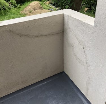Mur extérieur partiellement réparé avec enduit – fissures comblées avant finition.