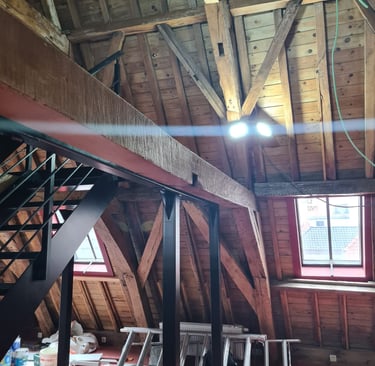 Ossature métallique avec escalier sur mesure, installée sous une charpente bois apparente dans des c