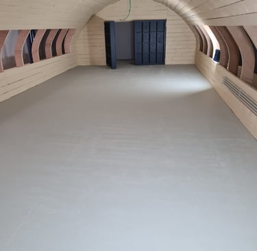 Pièce aménagée sous voûte en bois cintré avec finitions murales sur mesure et sol lisse – résultat f