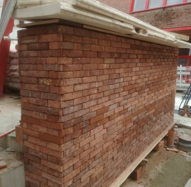 Mur en briques rouges en cours de montage, maçonnerie traditionnelle soignée sur chantier de rénovat