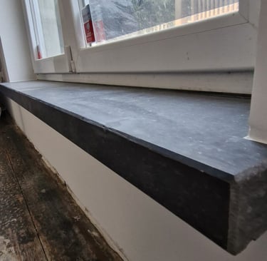 Appui de fenêtre en pierre bleue installé sous châssis PVC dans un logement rénové
