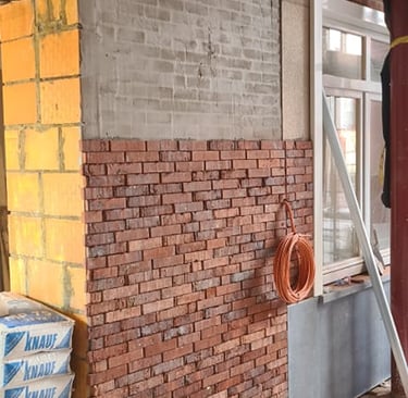 Rénovation de façade intérieure avec isolation thermique, parement en briques rouges et mur en béton