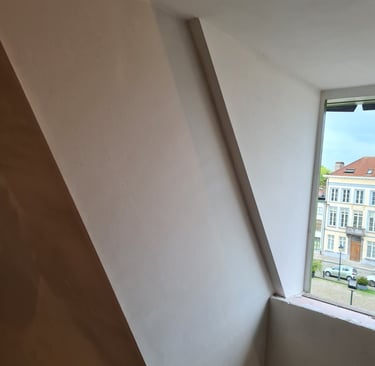 Plafonnage sur mur incliné avec finitions soignées autour d'une fenêtre de toit