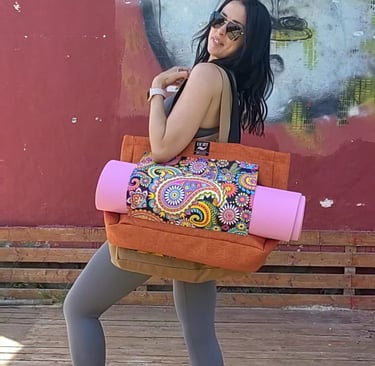a woman in tights and leggings, holding a yoga mat carrier bag