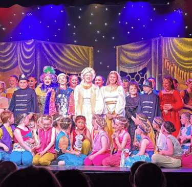 Group photo of the cast of Aladdin on stage at Theatr Colwyn