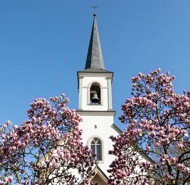 A serene sunrise over a quiet chapel surrounded by trees, symbolizing peace and devotion.