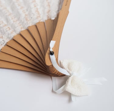 a white lace covered wooden hand fan 