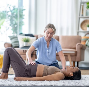 a woman in a blue shirt is helping another woman with a pelvic floor stretch