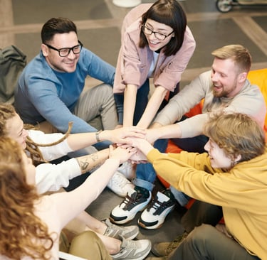 a group of people sitting around a group of people holding hands