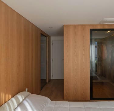 dormitorio calido, revestimiento pared madera clara, puerta vestido de vidrio y puerta de acceso ras