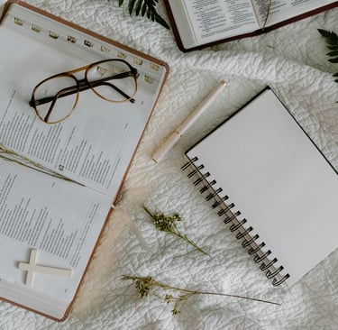 Open prayer journal and pen resting beside a Bible in soft morning window light — writing your praye