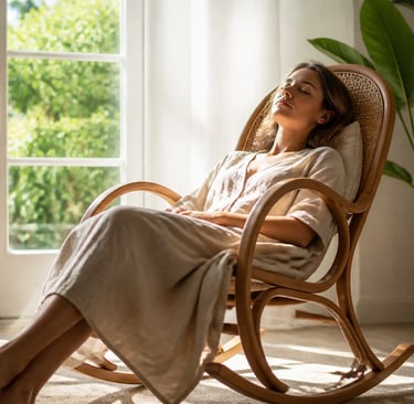 A woman relaxes in a wooden rocking chair by a sunny window for home wellness.