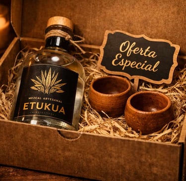 Caja regalo premium de Etukua abierta, mostrando una botella de mezcal artesanal, dos copas de barro
