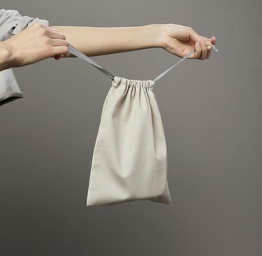 a person holding up a plain white draw-string bag