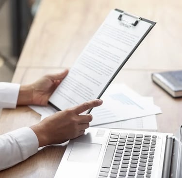 Pessoa segurando prancheta com relatório e computador