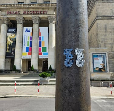 Zdjęcie dwóch magnesów z Syrenkami Warszawskimi na tle Pałacu młodzieży.