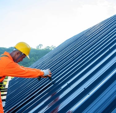 worker wearing protective equipment installing a metal roof