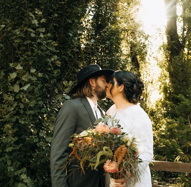 Romantic wedding couple kissing in natural greenery garden setting