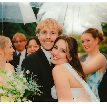 Bride and groom celebrating with their bridal party under clear umbrellas